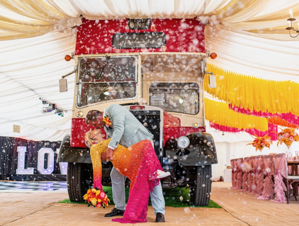 a couple standing in front of of the bus at Deckerdence doing a drop kiss with bubbles